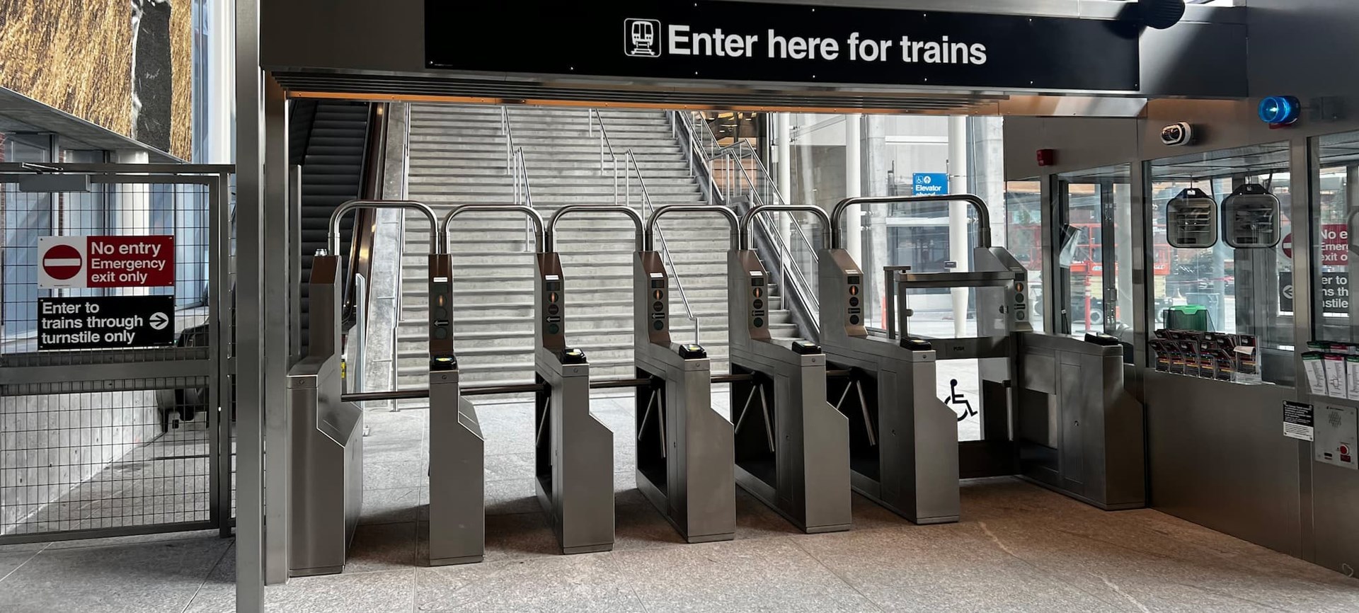 Fare gates in a row at the Damen Green Line station. A sign says Enter here for trains.
