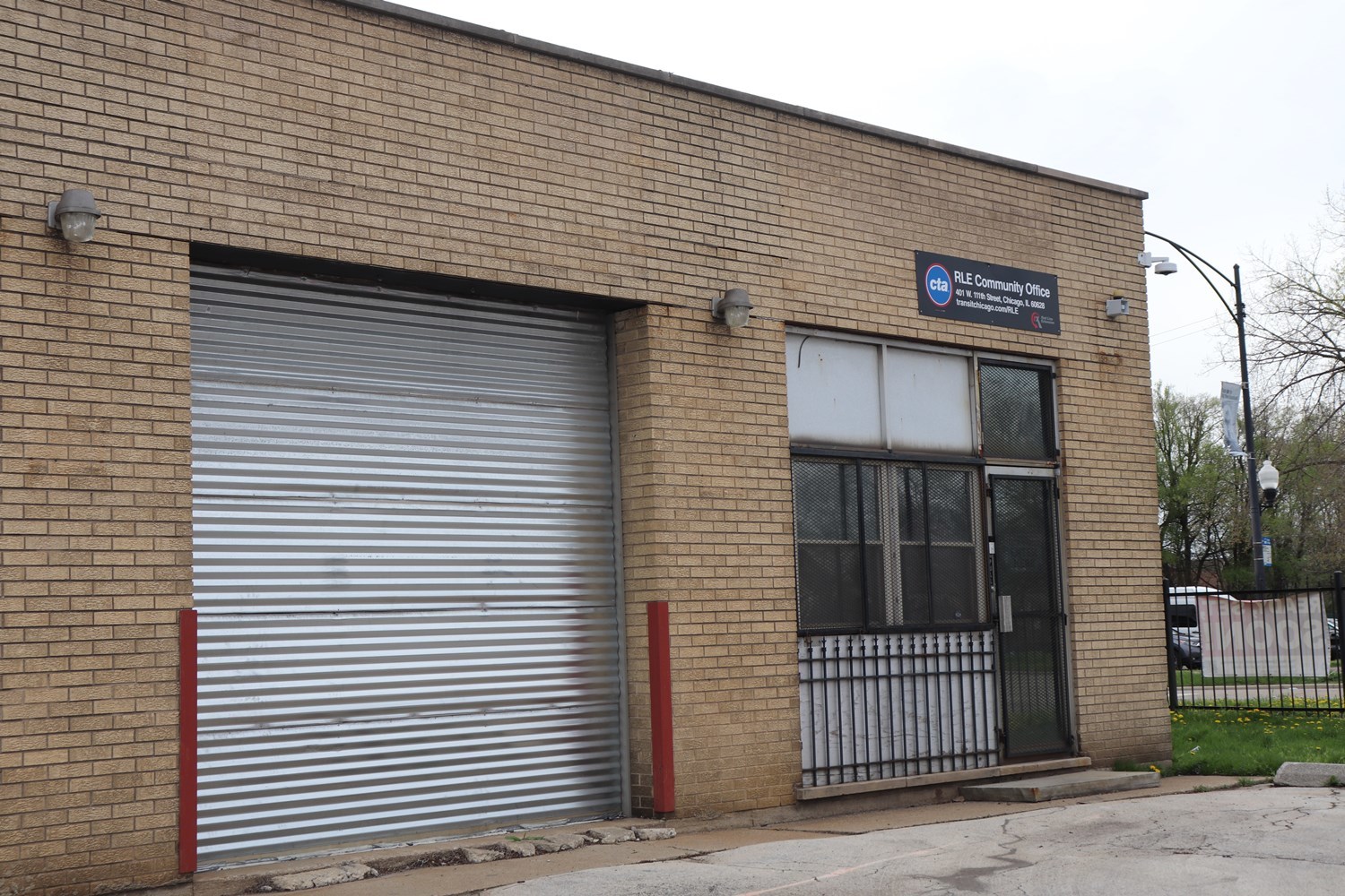 The East side of RLE Community Office seen from the South East, large garage doors are accompanied by the entrence with the RLE Community Office sign prominently above the doorway. 