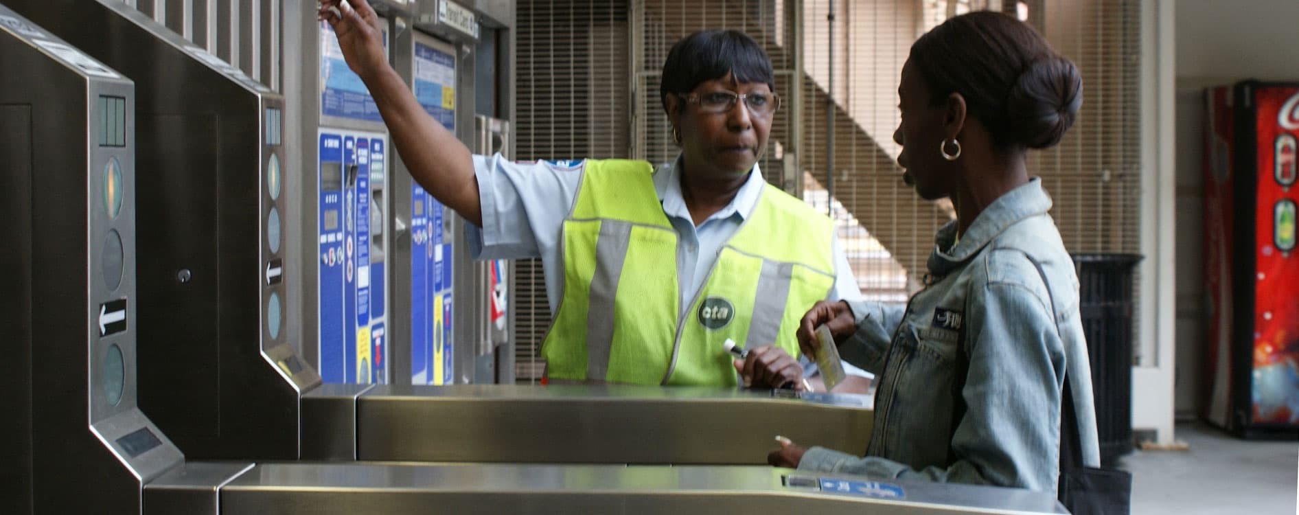 A staff member helping a customer in a rail station.
