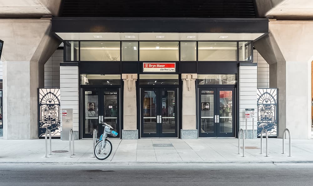 Three station doors flanked by murals, with bike racks in front.